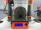 A Basalt Moon Dust Filamet™ 3D printer with a helmet on top by The Virtual Foundry.
